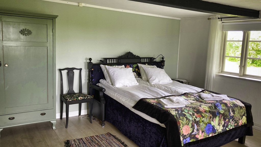 Bäddad dubbelsäng med fönster i bakgrunden