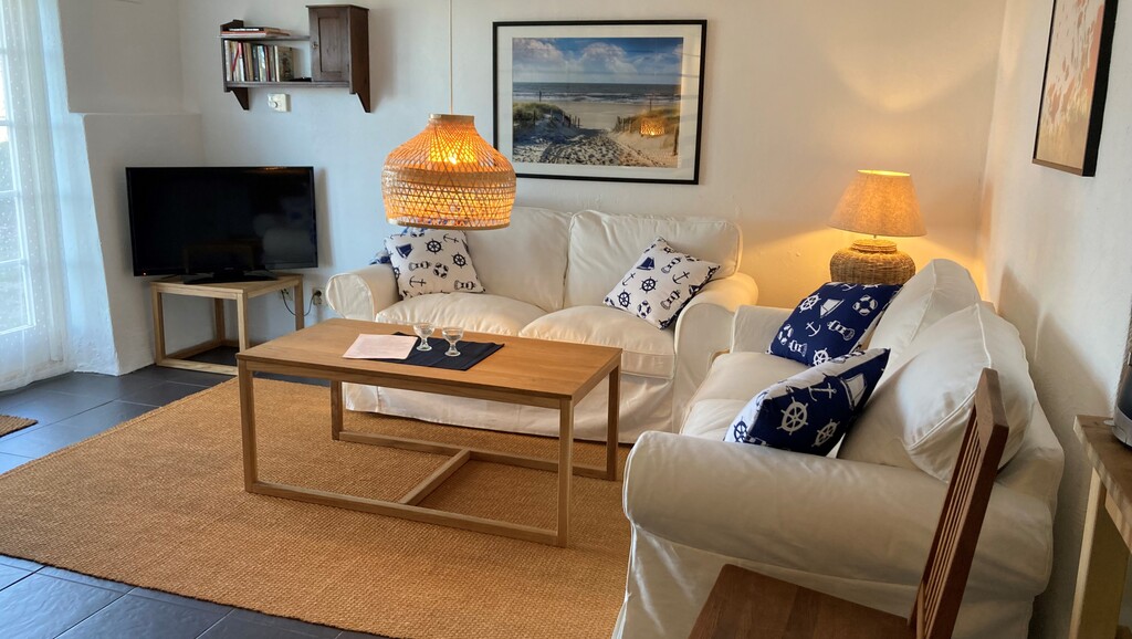 Ljus soffgrupp med kuddar, soffbord och tv i bakgrunden