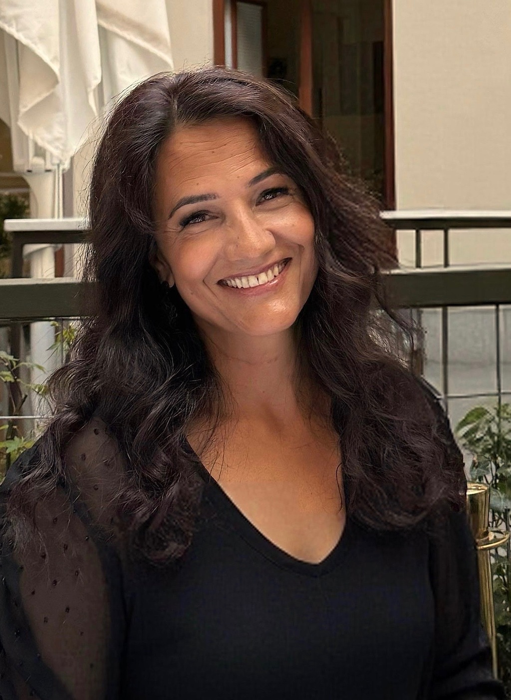 Bild på Karin Sjöholm, leende medelålders kvinna med mörkt, långt hår